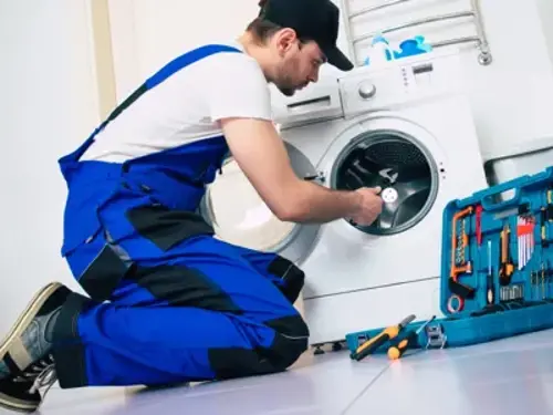 En man fixar en tvättmaskin i ett rum.