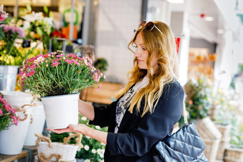 En kvinna håller i en krukväxt i en blomsteraffär.