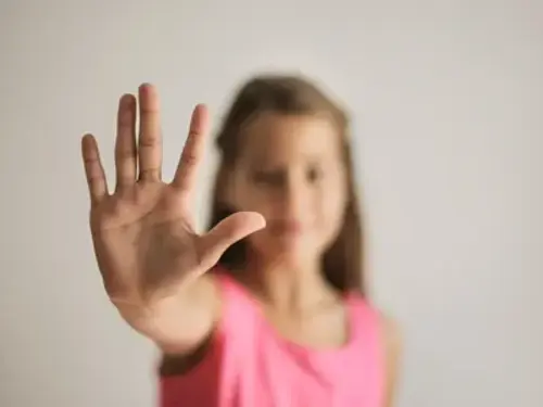 En ung flicka håller upp sin hand i luften.