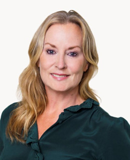 En kvinna i grön skjorta poserar för en bild.