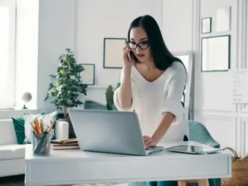 En kvinna sitter vid ett bord och använder en bärbar dator.