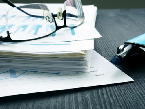 Ett par glasögon som sitter på en hög med papper.